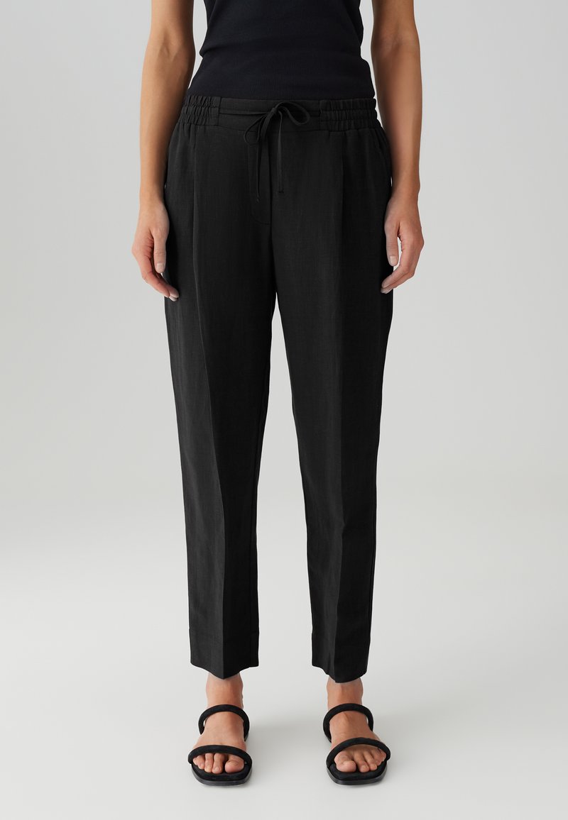 Schwarze, leichte Hose mit einem elastischen Bund und verstellbarem Kordelzug, mit schmal zulaufendem Bein und Bundfalten.
