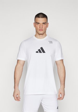 Witte katoenen t-shirt met korte mouwen. Heeft een zwart adidas logo en de tekst "Football Futbol Soccer" gedrukt op de borst.