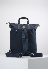 Mochila azul marino hecha de tela duradera, con asa superior, correas ajustables y bolsillos con cremallera para un almacenamiento seguro.
