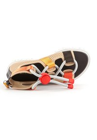 Des sandales avec une tige en maille beige et marron, ornées de sangles orange et jaunes. Comprennent des lacets élastiques et un bouton de réglage rouge.