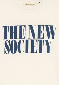 Camiseta de algodón blanca con texto en negrita de color navy que dice "LA NUEVA SOCIEDAD". Cuello redondo. Diseño simple y limpio sin patrones o acentos adicionales.