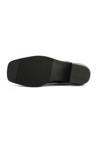 Suela de zapato negra con superficie texturizada y estriada; forma rectangular con borde superior liso; diseñada para proporcionar agarre y estabilidad.