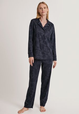 Completo pigiama blu navy con motivo floreale, composto da una maglietta con bottoni e pantaloni con elastico in vita. Tessuto morbido con maniche lunghe e polsini.