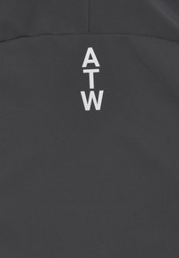 Dunkelgrauer Stoff mit glatter Textur, auf dessen Rückseite die weißen Buchstaben "ATW" vertikal, zentriert und in Fettdruck aufgedruckt sind.