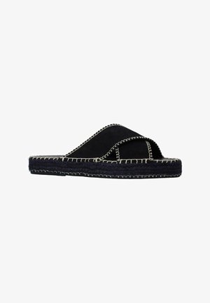 Sandales à glissière en suède noir avec un design à bandes croisées, présentant des coutures blanches contrastantes et une semelle en jute tissée pour une texture et une durabilité.
