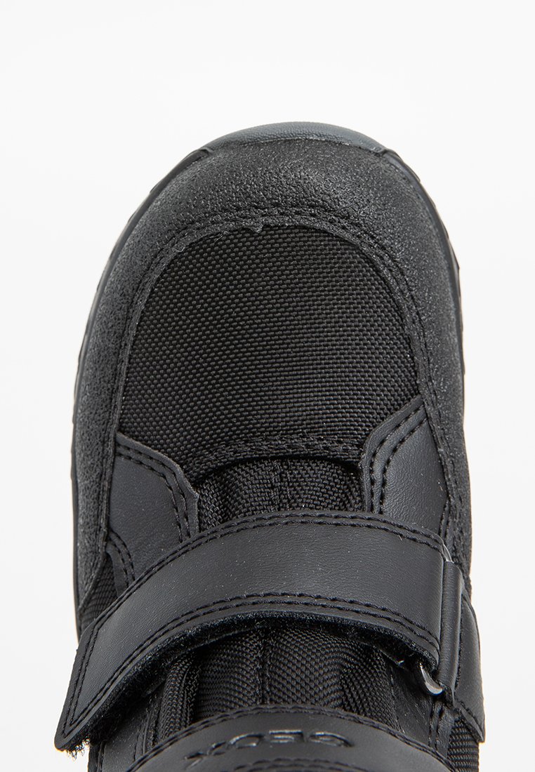 Czarne obuwie z teksturowanym skórzanym czubkiem i siateczkowymi detalami. Posiada rzep do bezpiecznego dopasowania i wyściełany kołnierz.