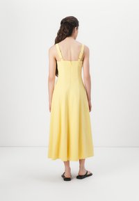 Vestido amarillo de mezcla de lino con un corsé ajustado, tirantes ajustables y una falda midi acampanada. Cierre de cremallera en la parte posterior, textura suave.