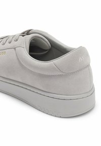 Baskets en daim gris clair avec lacets, semelle épaisse et logo doré "HUGO" sur le côté, vues de l'arrière en angle latéral.