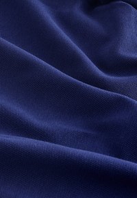 Temno modro blago z teksturiranim, tkanym vzorcem, ki prikazuje gube in pregibe za globino. Trajna material s gladko površino.