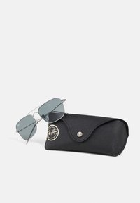 Ray-Ban sunglasses with gray lenses, silver metal frame, and angular design beside a black protective case featuring a logo and snap closure.