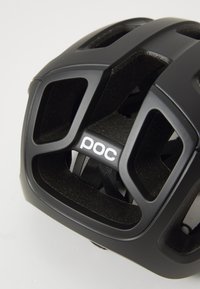 Casco da ciclismo nero con fori di ventilazione, imbottitura interna testurizzata e finitura liscia. Presenta un prominente logo "poc" bianco sul davanti.