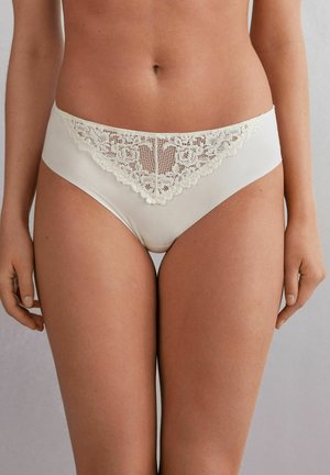 Helle beigefarbene Panties mit einem transparenten Spitzebesatz am Bund, verziert mit floralen Mustern und gewellten Kanten. Glattes Material und mittelhoher Schnitt.