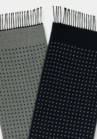 Dwa wzorzyste szaliki w ciemnym granacie i szarości. Oba mają wzór w kropki i frędzle na krawędziach, wykonane z miękkiego, teksturowanego dzianego materiału.