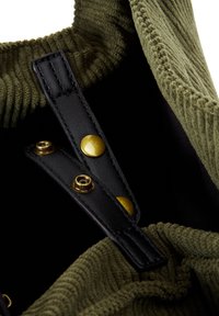 Groene corduroy tasinterieur met zwarte leren riemen en goudkleurige hardware. Voorzien van drukknoopsluitingen en een gestructureerde voering.