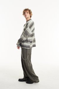 Megzta megura su šviesiai pilkomis ir kreminėmis juostelėmis, plačiomis rankovėmis. Sujungta su šlaito spalvos kelnėmis su šonine kišenėle ir grandinėlės detalėmis. Juodos platforminės bateliai.