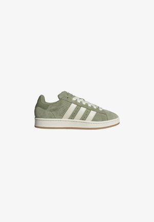 Green suede sneaker with white leather stripes, rounded toe, and flat rubber sole. Features perforated detailing and contrasting accents.
