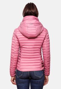 Růžová péřová bunda s kapucí, prošívaný design, hladká textura a boční detaily. V kombinaci s tmavými džíny.