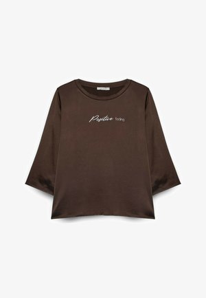 T-shirt marrone corta con maniche a tre quarti; presenta testo ricamato bianco "Positive feeling" sul davanti. Tessuto liscio.