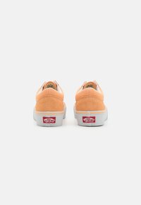 Oransje semsket sneakers med hvit hæltab, hvit såle og rød Vans-logo bak, med et klassisk low-top design.