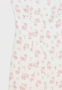 White fabric with a fitted shape featuring a delicate pink and green floral print in clusters, highlighting seam details and texture.