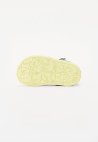 Gul gummisåle med et teksturert mønster som viser dyreillustrasjoner og merkenavnet "Camper" præget. Flat og bred form.