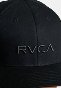 Black cap made from durable fabric with a structured shape. Features embroidered "RVCA" logo in a contrasting shade and textured surface.