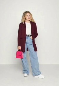 Bordo blazer, bela majica, svetlo modri kavbojke z visokim pasom, roza torbica in bele teniske. Mehka tkanina, krojen dizajn.