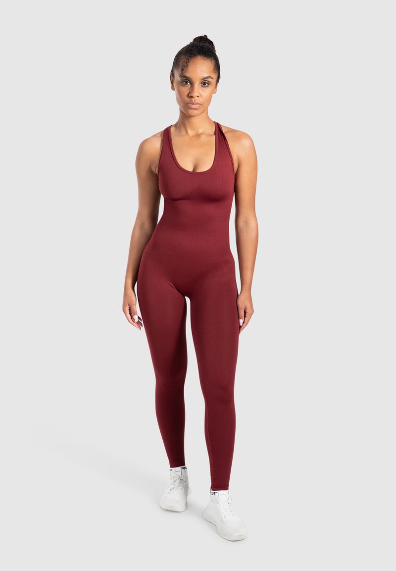 Vinröd body med en åtsittande design, breda axelband och en slät textur. Kombinerad med vita sportskor. Enkelt och figurnära stil.