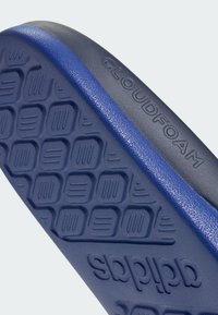 Cloudfoam-sål med et fremtrædende sekskantet mønster, der har en glat blå overflade og en tekstureret mellemsål. "Cloudfoam" og "adidas" er præget.