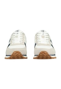 Coppia di sneaker bianche e beige con dettagli blu navy, lacci bianchi e suole in gomma marrone con motivo ondulato, viste frontalmente su sfondo bianco.