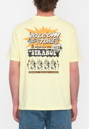 Yellow cotton t-shirt with a graphic design featuring the text "VOLCOM & THE STONES" and a skeleton dance motif on the back.