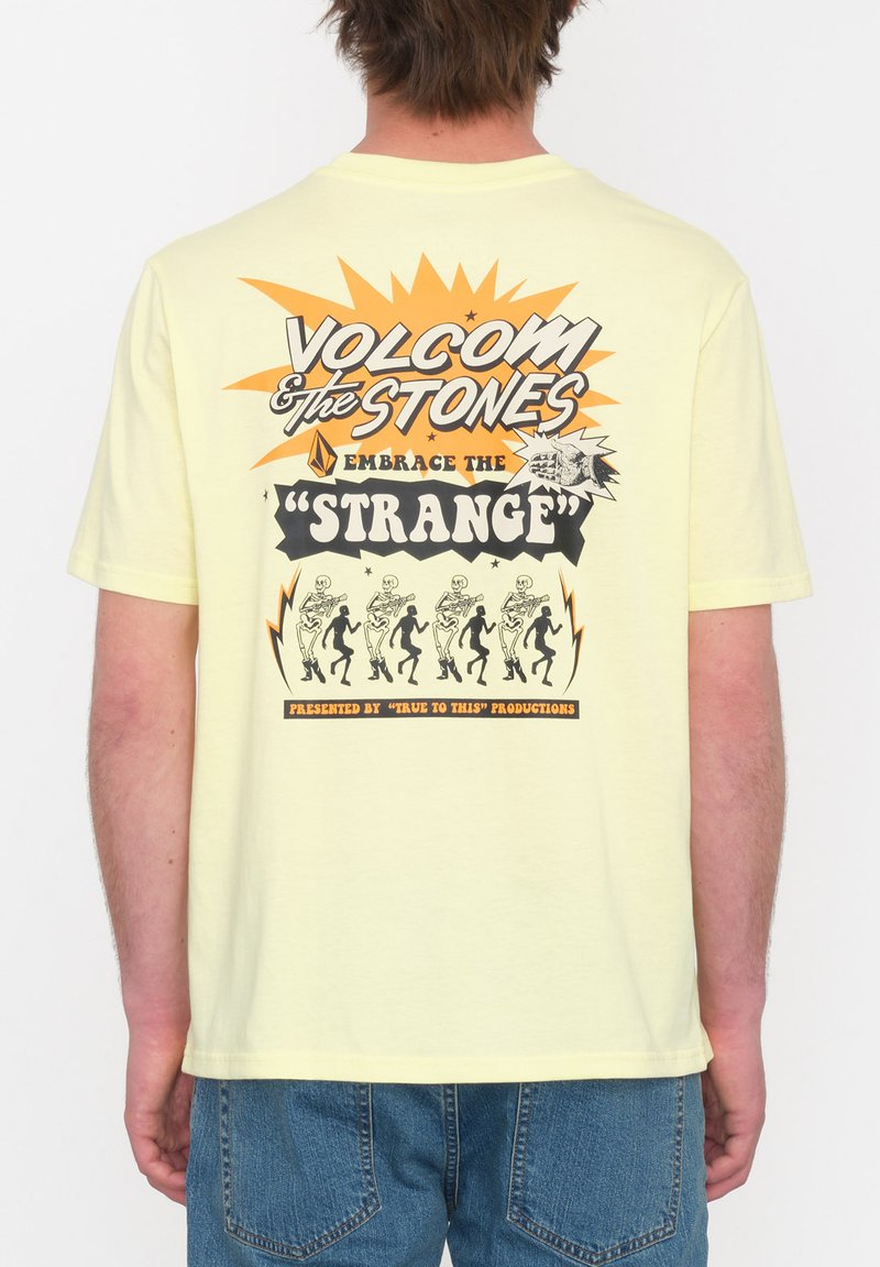 Gul bomuld t-shirt med et grafisk design, der viser teksten "VOLCOM & THE STONES" og et skeletdansemotiv på ryggen.