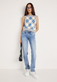 Αύτη η αμάνικη μπλούζα με καρό σχέδιο διαθέτει μπλε και κρεμ χρώματα. Συνδυάζεται με απευθείας μπλε τζιν και λευκά αθλητικά παπούτσια. Μαύρη τσάντα.