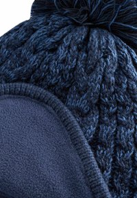 Bonnet tricoté bleu avec un motif de câble texturé, doté d'une doublure en polaire douce et d'un pompon sur le dessus. Ourlet renforcé pour plus de durabilité.
