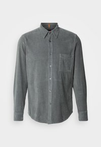 Chemise homme en velours côtelé gris foncé manches longues avec col pointu et poche poitrine sur fond blanc.
