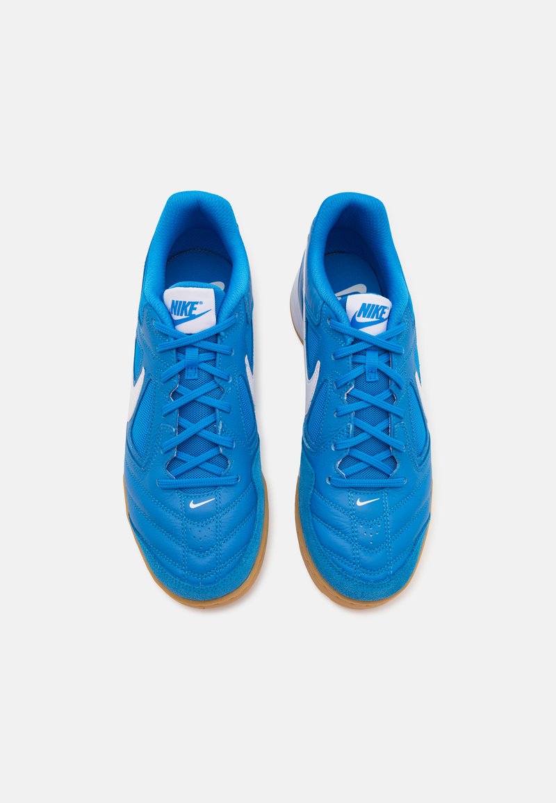 Zapatillas deportivas sintéticas azules con una superficie texturizada, diseño de cordones, logo de Nike en blanco y suela de goma.