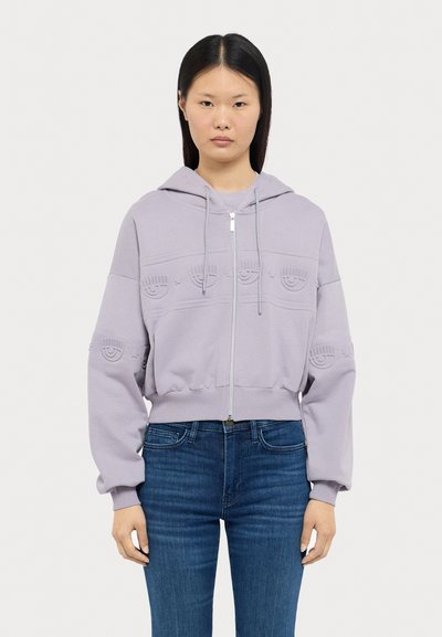 Fato de treino com fecho em roxo lavanda, em material suave, com punhos canelados, apresentando um padrão de rostos sorridentes em relevo na frente e um capuz com cordão.