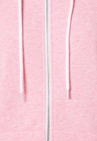 Felpa rosa con zip realizzata in materiale morbido, con coulisse bianca e zip argentata che corre sulla parte anteriore. Tessuto complessivamente liscio.