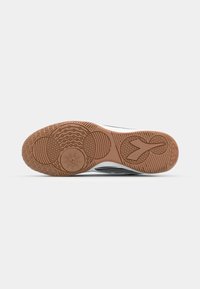 Sport shoe outsole with a textured rubber design. Features circular and linear patterns in light brown and black for grip and traction.