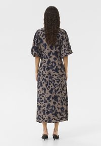 Rochie midi dintr-un material maro deschis cu un model floral bleumarin; are o croială lejeră și mâneci scurte, voluminoase.