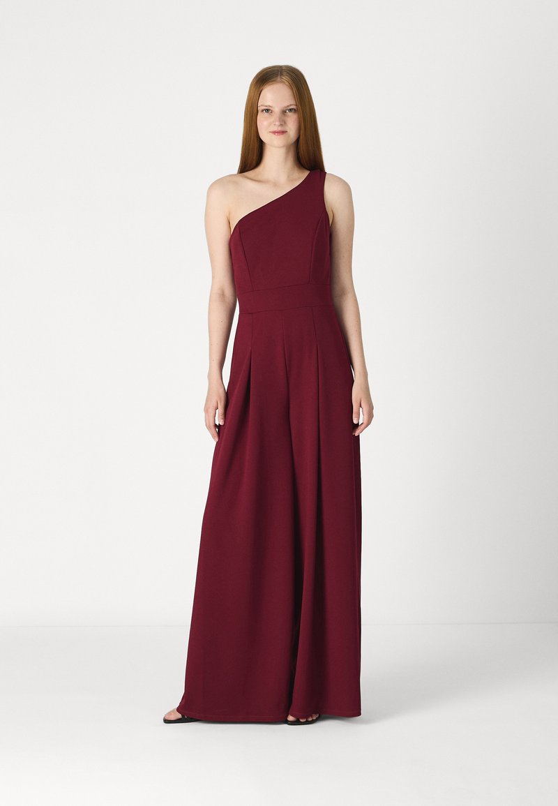 Combinaison bordeaux à une épaule en tissu doux. Présente un buste ajusté, des jambes larges plissées et un design minimaliste.