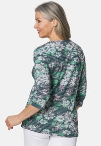 Langärmliges Oberteil mit floralen Mustern in Grün, Weiß und Lila auf Streifen, mit Rundhalsausschnitt und lockerer Passform. Weicher, leichter Stoff.