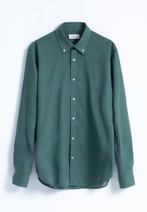 Camisa de manga larga verde bosque con cuello abotonado, botones en la parte frontal y un dobladillo ligeramente redondeado. Fabricada con una tela suave de textura lisa.