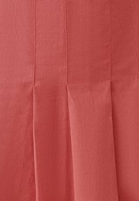 Korálově růžová lněná tkanina s vertikálními sklady, hladkou texturou a čistým, jednoduchým designem. Žádný výrazný kovový prvek nebo akcenty.