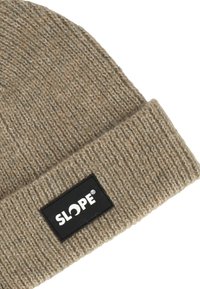 Beige neulottu pipo, jossa on käänneheitto ja musta suorakulmainen etiketti, jossa on valkoisella tekstillä sana "SLOPE".