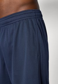 Marinefarbene Mesh-Sportshorts mit elastischem Bund, ausgestattet mit einem strukturierten Stoff und seitlichen Taschen. Ideal für Sport und Freizeitanlässe.