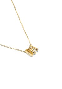 Collier en or avec une chaîne délicate et trois pendentifs : deux formes ovales polies et un pendentif orné de petites pierres claires.
