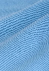 Hele sinine kangas peene soonilise tekstuuriga, millel on diagonaalsed koed. Sile pind, ühtlane värv ja nähtavate mustrite või aktsentideta.