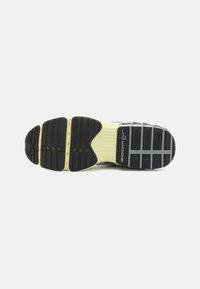 Semelle d'une chaussure de sport avec une bande de roulement en caoutchouc noir et gris, une semelle intermédiaire jaune, et le logo "Zoom Air" sur la partie du talon.