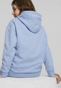 Svetlomodrá mikina s kapucňou, predným vreckom, rebrovanými manžetami a lemom. Má priestrannú kapucňu a mäkkú bavlnenú látku pre pohodlie.